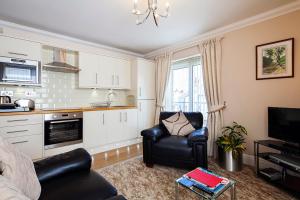 ein Wohnzimmer mit 2 Stühlen und eine Küche in der Unterkunft Burbage Holiday Lodge Apartment 4 in Blackpool