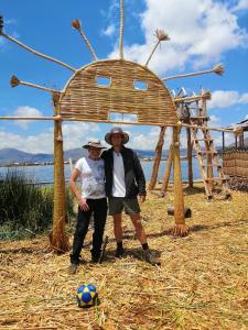 due uomini in piedi sotto una struttura di legno con un pallone da calcio di Uros Lodge Lover Titiqaqa a Puno