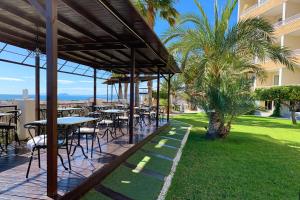 プエルト・デ・マサロンにあるRamada Resort by Wyndham Puerto de Mazarronのヤシの木があるパティオ(テーブル、椅子付)