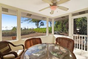 a screened in porch with a glass table and chairs at Playa Casanas North in Holmes Beach