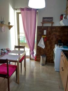 eine Küche mit einem Tisch und einem rosa Vorhang in der Unterkunft City Break Nearby Metro And Bus Express Airport in Athen