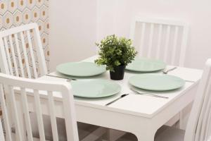 einem weißen Tisch mit vier Platten und einer Topfpflanze in der Unterkunft caput mundi in Krakau