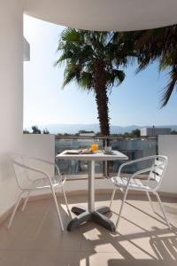 a table and two chairs on a balcony with a palm tree at Aegean Blu Hotel & Apartments in Kos Town