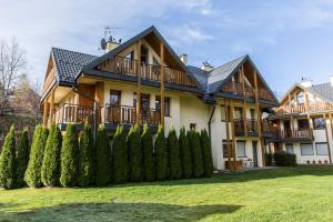 uma casa grande com uma cerca em frente em TatryTop Apartamenty Comfort em Zakopane