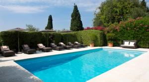 una piscina con tumbonas y sillas en un jardín en Bastide Saint Antoine - Relais & Châteaux, en Grasse