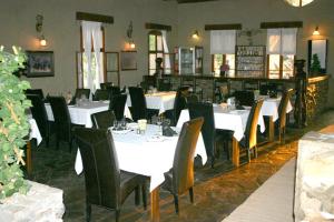 Fort Sesfontein Lodge & Safaris في Sesfontein: غرفة طعام مع طاولات بيضاء وكراسي سوداء