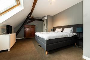 a bedroom with a large bed and a television at De Pastorie Bed & Breakfast in Roermond