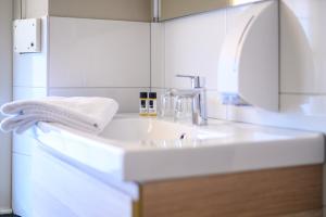 a white bathroom with a sink and a towel at De Pastorie Bed & Breakfast in Roermond