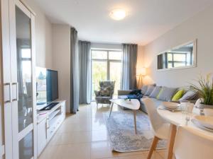 a living room with a couch and a tv at VacationClub – Diune Apartment 13 in Kołobrzeg