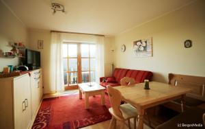 Appartement Hauzenberg-Panorama في هاوتسنبرغ: غرفة معيشة مع طاولة وأريكة حمراء