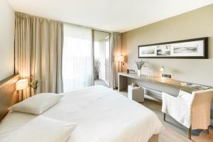 a bedroom with a large white bed and a desk at La Gree Des Landes - Eco-Hotel-Spa Yves Rocher in Cournon