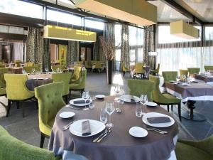 ブリニョールにあるMercure Brignoles Golf de Barbaroux & Spaのテーブルと椅子、皿、ワイングラスが備わるレストラン
