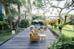 a wooden walkway with chairs and tables and trees at Byasa Ubud in Ubud