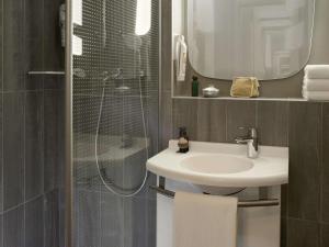 a bathroom with a sink and a shower with a mirror at ibis Velizy Jouy-En-Josas in Jouy-en-Josas