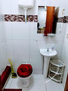 La salle de bains est pourvue de toilettes rouges et d'un lavabo. dans l'établissement Posada Bavaria, à Trinidad