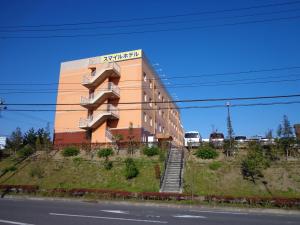 a building on top of a hill next to a road at Smile Hotel Sendai Izumi IC in Sendai