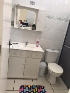 een badkamer met een wastafel, een toilet en een spiegel bij Lindo Apto. Frente Praia (Cond. Dom Felippe) in São Lourenço do Sul