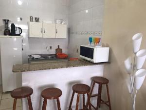 a kitchen with a counter with stools and a microwave at Lindo Apto. Frente Praia (Cond. Dom Felippe) in São Lourenço do Sul