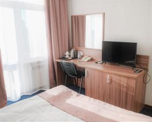 a hotel room with a bed and a television on a dresser at BOUTIQUE HOTEL 1967 AQSAI in Aksay