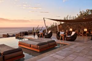 un patio con sofá, sillas y el océano en Mykonos Bliss - Cozy Suites, Adults Only Hotel, en Playa Kalo Livadi
