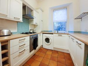 a kitchen with white cabinets and a dishwasher at Linburn House Apartment in Dunfermline