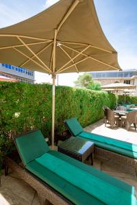 une terrasse avec un parasol, des chaises et une table dans l'établissement SG Premium Resort, à Arusha