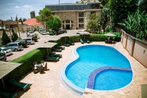 een groot zwembad met stoelen en een gebouw bij SG Premium Resort in Arusha