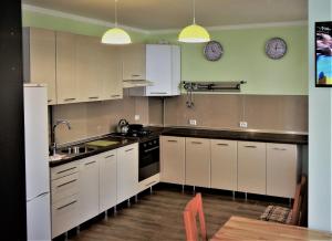 a kitchen with white cabinets and two clocks on the wall at Oroszvég in Mukacheve