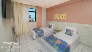 a hotel room with two beds and a television at Maredomus Hotel in Fortaleza