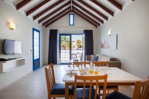 a dining room with a table and chairs and a living room at Grupotel Cinco Plazas in Puerto del Carmen