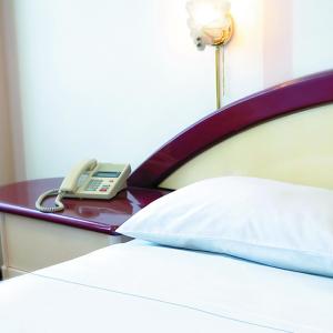 a bed with a phone on a table next to it at Americana Hotel in Cochabamba