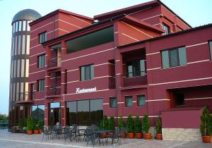 a red building with tables and chairs in front of it at Prestige Hotel in Belene