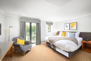 a bedroom with a large bed and a chair at voco Oxford Thames by IHG in Oxford