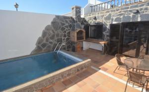 a hot tub on a patio with a stone wall at Far-Island Villa in Playa Blanca