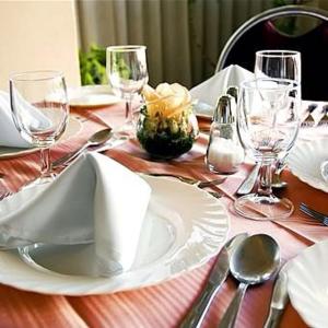 a wooden table with a white plate and wine glasses at Americana Hotel in Cochabamba