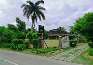 una señal frente a una casa con una palmera en Le Relax Beach Resort, en Grand'Anse Praslin