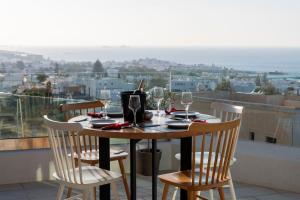 a table with chairs and wine glasses on a balcony at Sunset View Hotel in Parikia