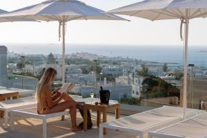 a woman sitting on a chair reading a book on a balcony at Sunset View Hotel in Parikia
