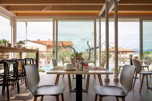 ein Esszimmer mit einem Tisch, Stühlen und Fenstern in der Unterkunft Hotel Villa Olivo Resort 3S in Bardolino