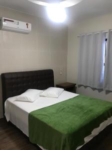 a bedroom with a bed with a green blanket on it at Casa - Próximo a UFSC e Centro - 5KM # in Florianópolis