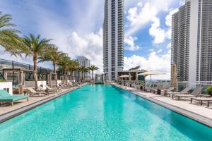 una piscina con sillas, palmeras y edificios en Modern 3 bedroom at Hollywood Beach Resort 28th floor, en Hallandale Beach