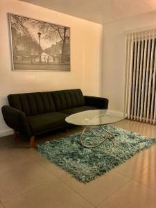un soggiorno con divano nero e tavolo in vetro di Explore Wynwood 2bedrooms and free parking a Miami