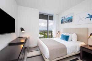 a bedroom with a bed and a desk and a television at Ocean Breeze Retreat - Pool Gym Access Views in Hallandale Beach +20 photos