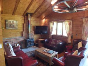 a living room with leather couches and a tv at Walnut Log Cabin in Swanage