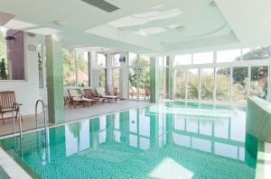a swimming pool in a house with glass windows at Hotel Kardosfa in Zselickisfalud