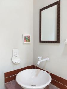 ein Badezimmer mit einem weißen Waschbecken und einem Spiegel in der Unterkunft Chalé da Mangueira in Vale do Capao