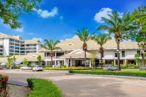 a building with palm trees in front of a parking lot at The Royal Gems Golf Resort in Nakhon Pathom