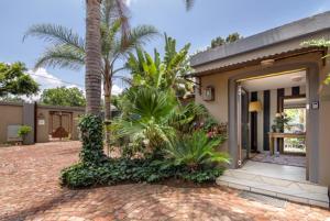 a house with a courtyard with palm trees and a door at The Minimalist Studio B in Benoni