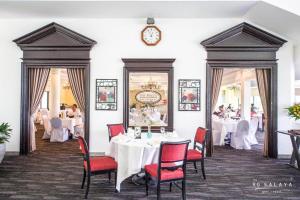 a restaurant with white tables and red chairs and a clock at The Royal Gems Golf Resort in Nakhon Pathom