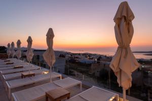 a row of tables and umbrellas on a roof with the sunset at Sunset View Hotel in Parikia